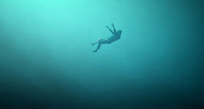 an image showing Einar from the short film We Came From the Sea drifting down through teal water